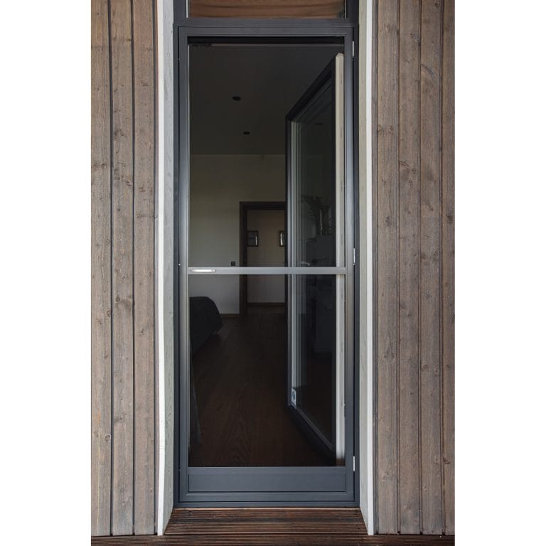 En Myggnät dörr - öppningsbar med en mörk metallram är placerad i en trävägg och visar det inre rummet genom sitt glas.