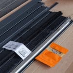 Parts of the Insect screen door - foldable: metal/plastic frames, black mesh, screws, and an orange pouch on cardboard.