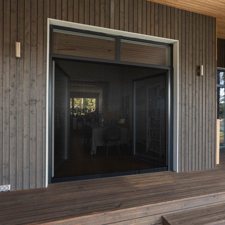 Foldable insect screen doors installed on a modern wooden patio door with vertical panels and outdoor lighting.