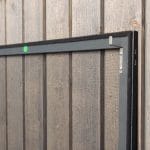 Lähikuva Hyttysverkko ikkunaan - kehysmallista puuseinällä, jossa näkyy kehyksen vihreä pistetarra.