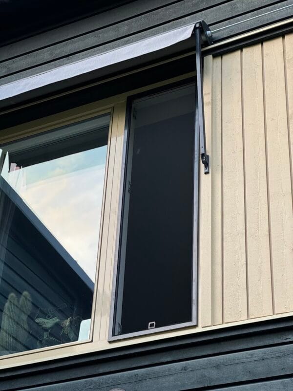 Ein teilweise geöffnetes Fenster mit insektu sieti und einem eingezogenen Fliegengitter an einer Außenwand eines Gebäudes mit vertikaler und horizontaler Verkleidung.